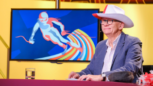 Oliver Baier sitzt im "Was gibt es Neues?"-Studio und trägt einen Cowboy-Hut.