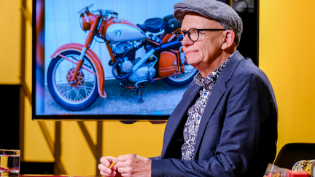 Oliver Baier sitzt vor einem Bildschirm, in dem ein Motorrad zu sehen ist. 