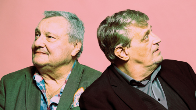 Zwei Männer stehen Rücken an Rücken und schauen in entgegengesetzte Richtungen.