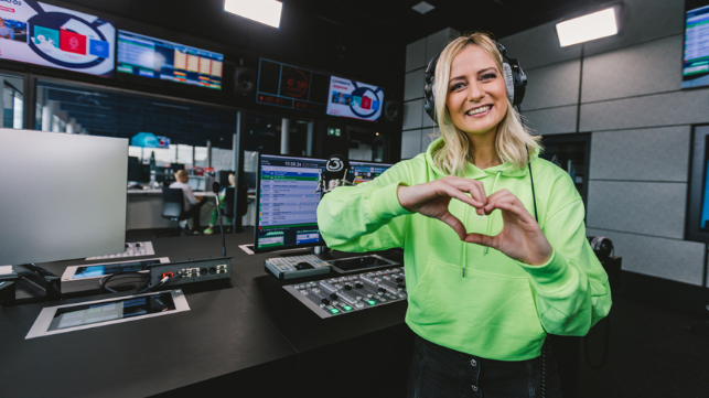 Im Ö3-Studio formt Moderatorin Tina Ritschl mit Ihren Händen ein Herz in Richtung der Betrachter:innen