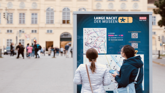 Zwei Frauen stehen vor einer Map mit allen teilnehmenden Museen